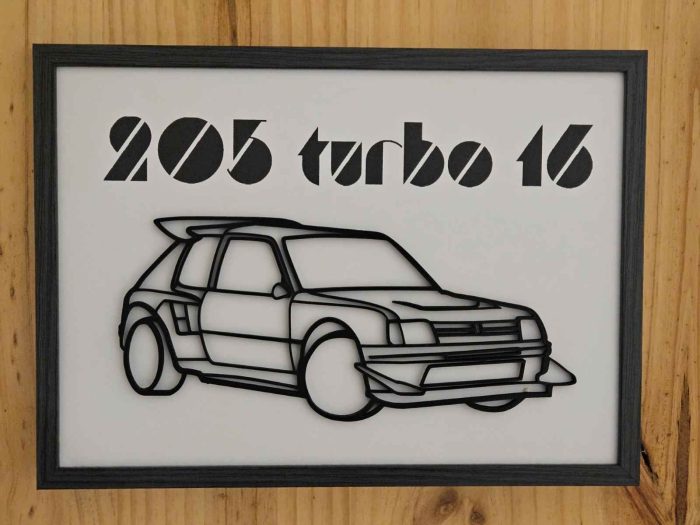 Un cadre A4 accroché à une paroi de meuble représentant une Peugeot 205 turbo 16.